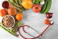 Frame made with stethoscope, fresh fruits and vegetables on wooden background. Healthy food concept Royalty Free Stock Photo