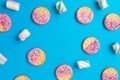 Frame made of tasty cookies with pink glaze and marshmallow on blue background. Flat lay. top view. Royalty Free Stock Photo