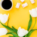 Frame made of white tulips flowers with mug of coffee and marshmallows on yellow background. Floral concept. Flat lay, top view. Royalty Free Stock Photo