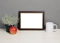 Frame mockup with plant pot, mug and apple on wooden shelf Royalty Free Stock Photo