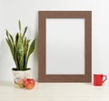 Frame mockup with plant pot, mug and apple on wooden shelf Royalty Free Stock Photo