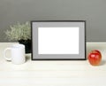 Frame mockup with plant pot, mug and apple on wooden shelf Royalty Free Stock Photo