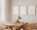 Frame mockup in Scandinavian dining room design, rattan chairs and wooden dining table on bright beige interior background Royalty Free Stock Photo