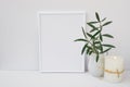 Frame mockup on white background, olive tree branches in ceramic pitcher, candle, styled image Royalty Free Stock Photo