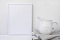 Frame mockup, white vintage pitcher on stack of linen towels, minimalist clean styled image