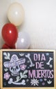 The frame is painted with a skull and flowers Day of the dead, balloons in the background