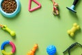 Frame of pet accessories, dry feed in bowl, toys on green table. Flat lay, top view. Pet shop banner design