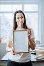 Frame picture, poster, diploma, certificate mockup in female hands. Young brunette woman holding empty blank wooden Royalty Free Stock Photo