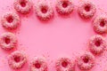 Frame of pink glazed donutes with sprinkles, top view