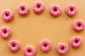 Frame of pink glazed donutes with sprinkles, top view