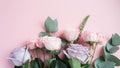 Frame of purple and pink roses, white Lisianthus and different flowers on pink background