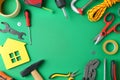 Frame of repair tools and house  on green background, flat lay. Space for text Royalty Free Stock Photo