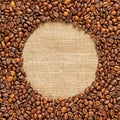 Frame of roasted coffee beans scattered around a burlap napkin inside. Royalty Free Stock Photo