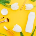 Frame of shampoo, perfume, cream and white tulips flowers on yellow background. Beauty composition. Flat lay, top view Royalty Free Stock Photo