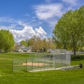 Frame Square Baseball or softball field against lush trees and buildings under cloudy sky Royalty Free Stock Photo