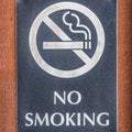 Frame Square Close up of a No Smoking sign screwed to a reddish brown wood surface