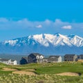 Frame Square Houses on a grassy hill with view of lake and snow peaked mountain