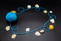 A Frame with threads and shells on a black background. A blue skein of thread