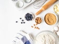 Frame of various baking ingredients - flour, eggs, sugar, butter, fresh blueberries, nuts, kitchen utensils and cupcake baking Royalty Free Stock Photo