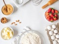 Frame of various baking ingredients - flour, eggs, sugar, butter, fresh strawberries, nuts, kitchen utensils and cupcake baking Royalty Free Stock Photo