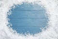 Frame of white snow on blue  background, top view with space for text. Christmas season Royalty Free Stock Photo