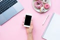 Frame woman`s hands holding white smartphone with black copyspace on pink background with other accessories. Feminine business mo Royalty Free Stock Photo