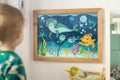 framed artwork of cartoon sea creatures on a bathroom wall near a child Royalty Free Stock Photo