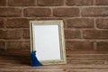 Framed blank card on wooden table. Brick wall.