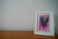 Framed drawing done by a child placed on a table at home