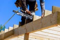 Framer worker installing beams using air nails hammer in a nailing wooden frame Royalty Free Stock Photo