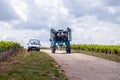 France Chablis 2019-06-21 Blue tractor to cultivate field, working on vineyard. Farmer watering vineyards with tractor