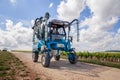 France Chablis 2019-06-21 Blue tractor to cultivate field, working on vineyard. Farmer watering vineyards with tractor