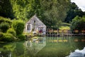 Pretty canal house, with walkway and red geraniums, reflected in the water. Francia.