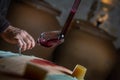 FRANCE, GIRONDE, SAINT-EMILION, SAMPLING A GLASS OF WINE IN A BARREL WITH A PIPETTE FOR TASTING AND VINIFICATION