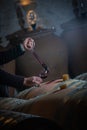 FRANCE, GIRONDE, SAINT-EMILION, SAMPLING A GLASS OF WINE IN A BARREL WITH A PIPETTE FOR TASTING AND VINIFICATION