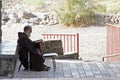 Franciscan monk sits in front of the Church of the Primacy of Saint Peter, Tabgha, Israel