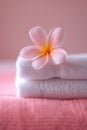 Frangipani flower on stack of white towels, a close-up of a delicate, pink plumeria flower with soft petals, on a white Royalty Free Stock Photo