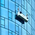 Window cleaners at work in a gondola suspended from steel cables on the facade of the Maintower in Frankfurt Royalty Free Stock Photo