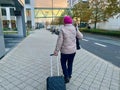 Frankfurt am Main, Germany - 08.11.2023: An elderly woman with suitcase and wearing beret is walking