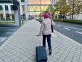 Frankfurt am Main, Germany - 08.11.2023: An elderly woman with suitcase and wearing beret is walking