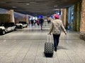 Frankfurt am Main, Germany - 08.11.2023: A woman with walks through an airport carrying a suitcase