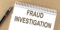 FRAUD INVESTIGATION text on a notepad with pen, business