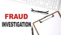 FRAUD INVESTIGATION text written on the white background with keyboard, paper sheet and pen