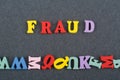 FRAUD word on black board background composed from colorful abc alphabet block wooden letters, copy space for ad text. Learning