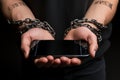 Fraudsters cuffed hands clutch phone, symbolizing addiction and illicit communications consequences