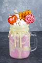 Freakshake from pink smoothie, cream. Monstershake with lollipops, waffles and marshmallow. Extreme milkshake in a Mason jar. Gray Royalty Free Stock Photo