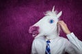 Freaky young man in comical mask stands on the purple background