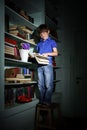 Freckled red-haired little boy searching book on bookcase