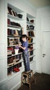 Freckled red-haired little boy searching book on bookcase