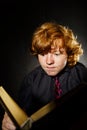 Freckled red-haired teenage boy reading book, education concept